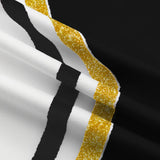 Close-up of the cheerleading uniform fabric showing black and white panels with a textured gold glitter stripe trim.