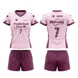 Custom pink and purple short sleeve V-neck pickleball apparel set with dot pattern, crew logo, number, and matching shorts.
