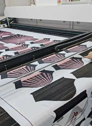 Large format printer producing custom heat transfer designs with team names and numbers on purple fabric panels.